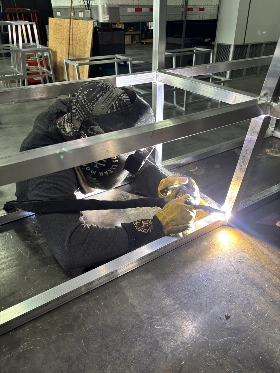 Shop welder fabricating a metal frame on a fixture table